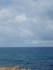 A glimpse of a rainbow touching down on the sea.
