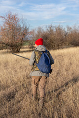 Mature hunter man holding a shotgun and walking through a field