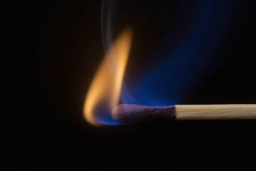 burning matchstick on black background