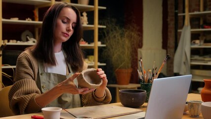 Pottery handmade art gallery potter artist designer sculptor student girl Caucasian woman decorator watch laptop video call online tutorial teach creative craft workshop clay modeling pot handcraft