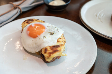A fried sunny-side-up egg topped with black pepper sits beautifully on melted cheese toast, served on a white plate. Perfect for promoting breakfast menus, cafes, or food blogs.