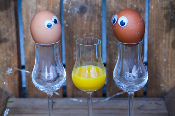 funny eggs with eggnog in a glass, wooden background