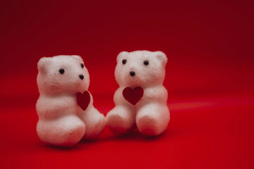 Two figures of polar bears with red hearts, red background