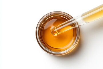 Top view of amber liquid in glass jar with dropper on white background