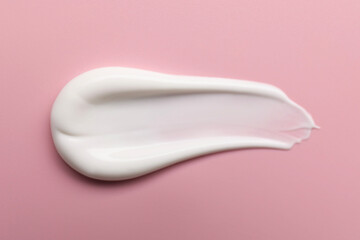 Cream on pink background, top view. Sample of cosmetic product