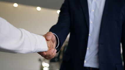 Two unrecognizable people in car salon hands close up Caucasian male client buyer man guy new automobile buying test drive bank credit handshaking woman dealer saleswoman female girl give key of auto