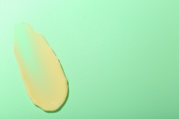 Cream sample on light green background, top view. Space for text