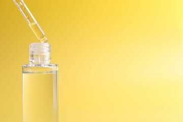 Dripping serum from pipette into bottle on yellow background, closeup. Space for text