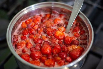 A nickel-plated saucepan with strawberries boiled in sugar syrup. Fruit preservation, jam