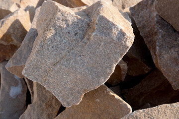 Natural stones stacked in a sunlit quarry reveal texture and beauty