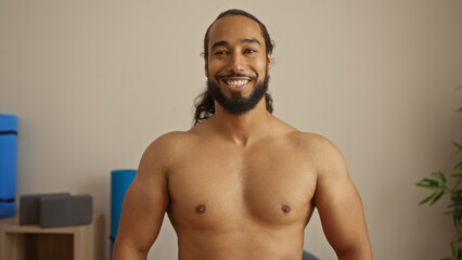 Smiling man with beard relaxing in wellness spa room, showcasing serenity and tranquility in a modern interior setting with soft lighting and earthy tones, conveying calm and peace.