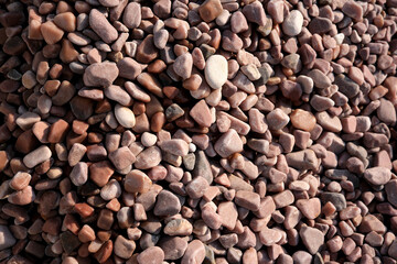 Varied textures of smooth pebbles in natural sunlight shining brightly