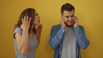 Woman yelling at man covering ears with hands against a yellow background illustrating relationship...