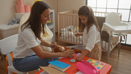 Woman playing daughter indoors room with toys in home, surrounded by cradle, baby essentials, and engaging in loving interaction in a cozy family environment.