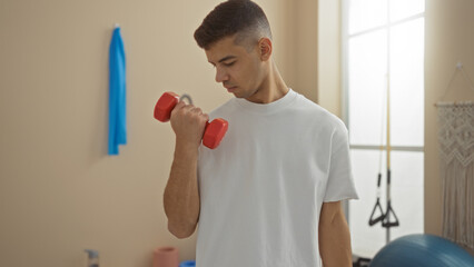 Man lifting dumbbell in gym focusing on upper body strength training in a bright indoor fitness...