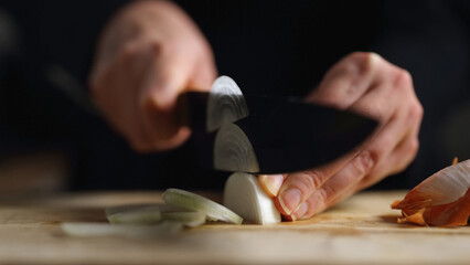 A woman cuts an onion into half rings.