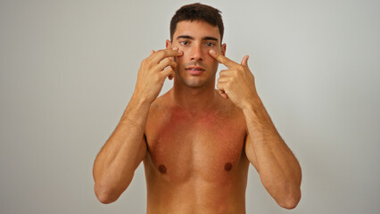 Fototapeta premium Young hispanic man with attractive features poses shirtless against isolated white background confidently maintaining direct eye contact