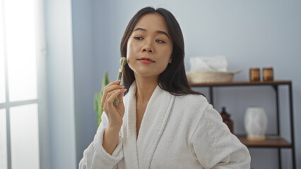Fototapeta premium Woman enjoying a facial massage with a jade roller in a serene spa room, wearing a white bathrobe inside a wellness center