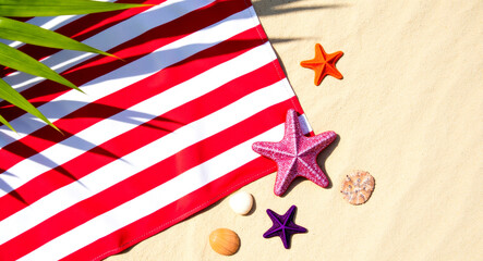 Fototapeta premium red and white striped beach towel with starfish and seashells on sandy beach