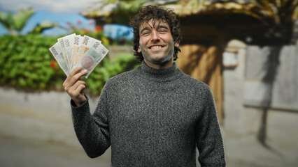 Man smiling on city street holding czech koruna banknotes outdoors conveying happiness and...