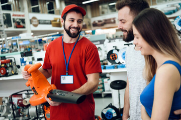 Salesman is showing couple of clients new leaf blower in power tools store.