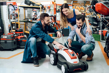 Salesman is demonstrating couple of clients new lawn mover in power tools store.