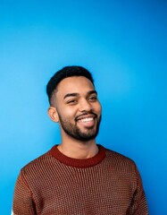Obraz premium Portrait of a man smiling wearing a sweater with plain soft blue background