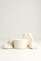 minimalist product display with cylindrical platform and three rocks