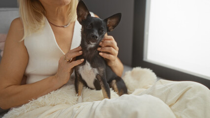 Woman holding chihuahua dog in living room showing affection