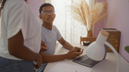 Fototapeta premium Young man talking to woman in living room while holding smartphone, symbolizing connection, family, and modern lifestyle in an indoor home setting with natural light and cozy decor