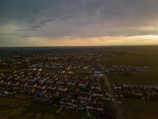 Rural settlement on the plain filmed from drone in cloudy summer weather. Beginning of a strong storm accompanied by thunder and lightning
