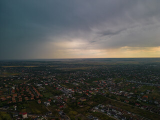 Fototapeta premium Rural settlement on the plain filmed from drone in cloudy summer weather. Beginning of a strong storm accompanied by thunder and lightning