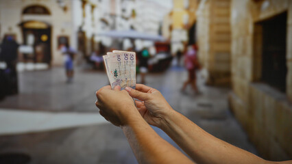 Man holding colombian pesos in an urban street setting, showcasing currency exchange outdoors with...