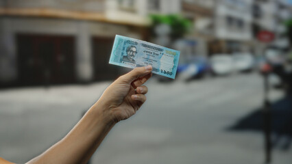 Hand holding bangladeshi taka banknote on bustling city street portrays finance and economy with...