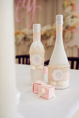 Elegant wedding table decor featuring decorated bottles with pearl and ribbon accents and small...