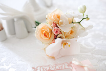 Wedding table with a bouquet of peach roses, pink roses, and white orchids.