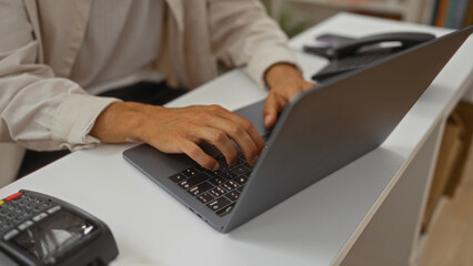 Young hispanic man using laptop inside a decor store