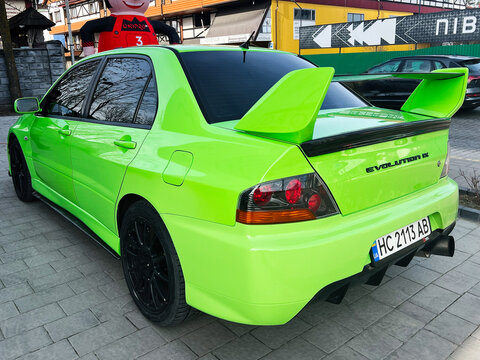 Lviv, Ukraine - February 12, 2025: Bright lime green Mitsubishi Lancer Evolution IX sports car showcased outdoors in a casual urban setting