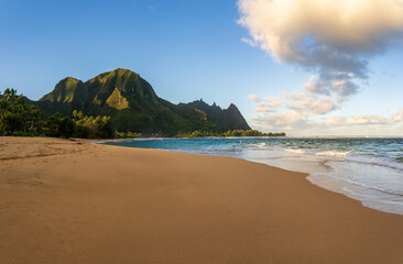 Beautiful Tunnels Beach at dawn on the island of Kauai, Hawaii with the vibrant sky reflecting on the wet sand.