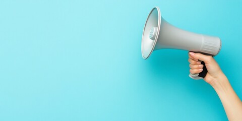 Hand holding megaphone against light blue background.
