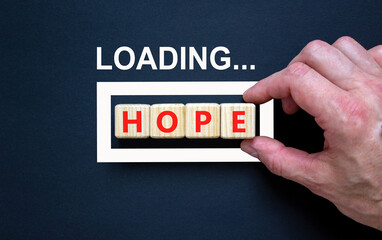 Hope symbol. Concept word Loading Hope on beautiful wooden blocks. Businessman hand. Beautiful black table black background. Business, lifestyle, support and hope concept. Copy space.