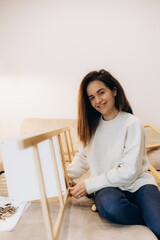 Young Woman Assembling Furniture at Home with a Smile