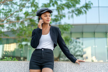 Asian Gen Z woman using phone in city street style. Stylish young female enjoying digital lifestyle...