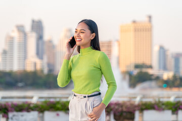 Fototapeta premium Young Asian Woman Talking on Phone in Modern City Outdoors