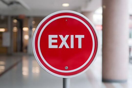 Bright red and white circular sign with the word "EXIT" in bold white letters. Provides direction and guidance for emergency situations or building navigation.