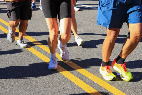 Legs of Runners Running Together During a Marathon