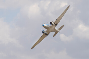 Vintage twin engine propeller Li-2 airplane flying in the cloudy sky