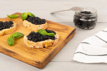 Bread slice with black caviar served on on wooden table