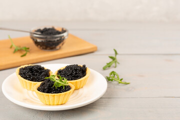 Tartlets with black caviar served on on wooden table