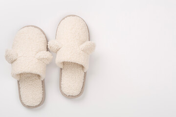 Soft teddy slippers on color background, top view